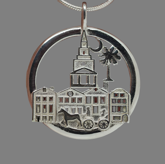 Silver pendant with architectural design held between fingers
