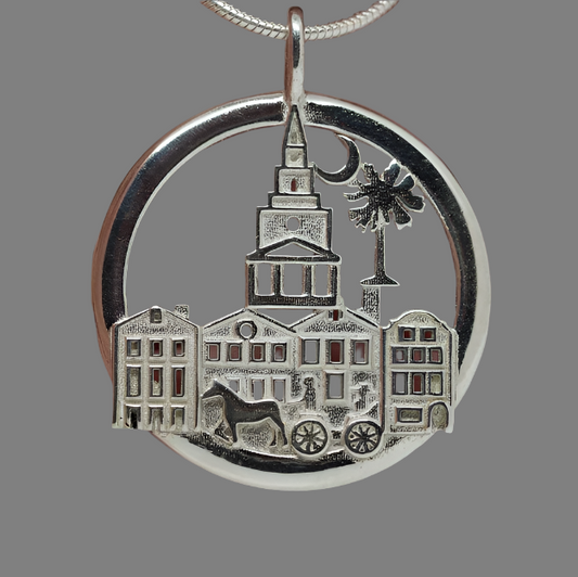 Silver pendant with architectural design held between fingers