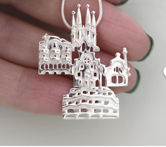Silver pendant of a architectural structure held between fingers
